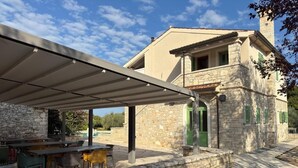 A stone building with a covered patio, outdoor seating, and a stone wall. - Relais Borgo San Nicolò (Vilanija)