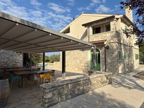 A stone building with a covered patio, outdoor seating, and a stone wall.