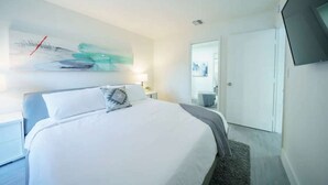 Een moderne hotelkamer met een groot bed, een flatscreen televisie en een minimalistische inrichting.