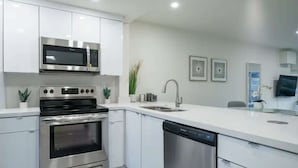 Een moderne keuken met roestvrijstalen apparatuur, witte keukenkastjes, een vaatwasser en een spoelbak.
