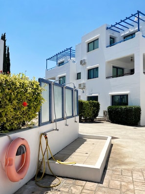 A modern building with white exterior walls, multiple windows, and balconies.