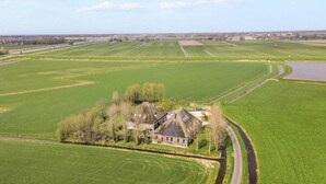 Ein weitläufiges Anwesen mit ausgedehnten grünen Feldern, einer kurvenreichen Straße und einem Gewässer.