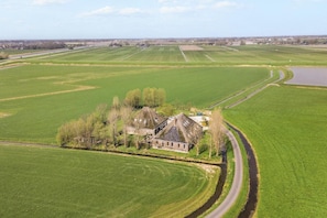 A large estate with expansive green fields, a winding road, and a body of water.