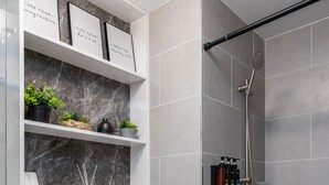 Une salle de bain moderne avec des toilettes, une douche, des étagères en marbre et un carrelage décoratif.