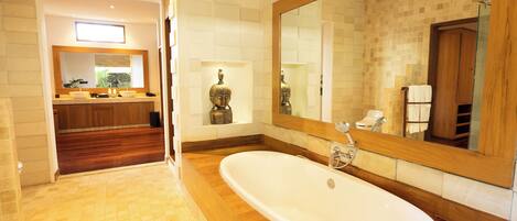 Un baño moderno con una bañera independiente grande, un tocador de madera y un espejo amplio.