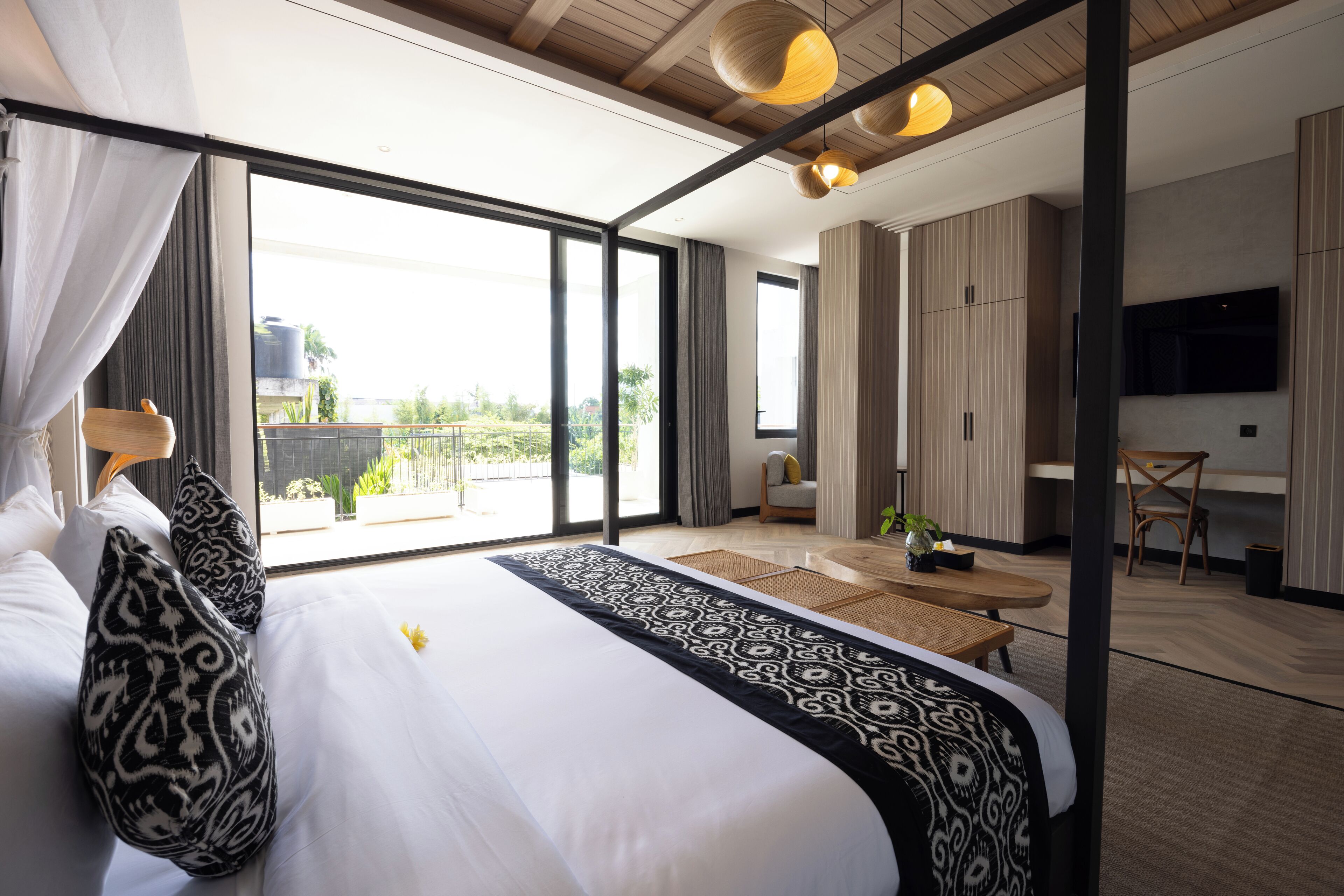 A modern hotel room with a large bed, a dining area, and a TV.