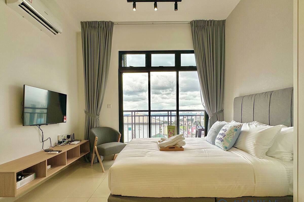 Habitación de hotel con cama, televisión y balcón con vistas.