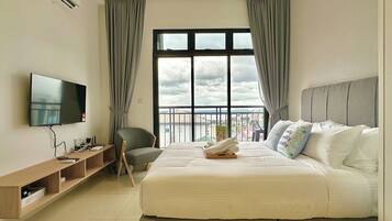A hotel room with a bed, TV, and a balcony with a view.