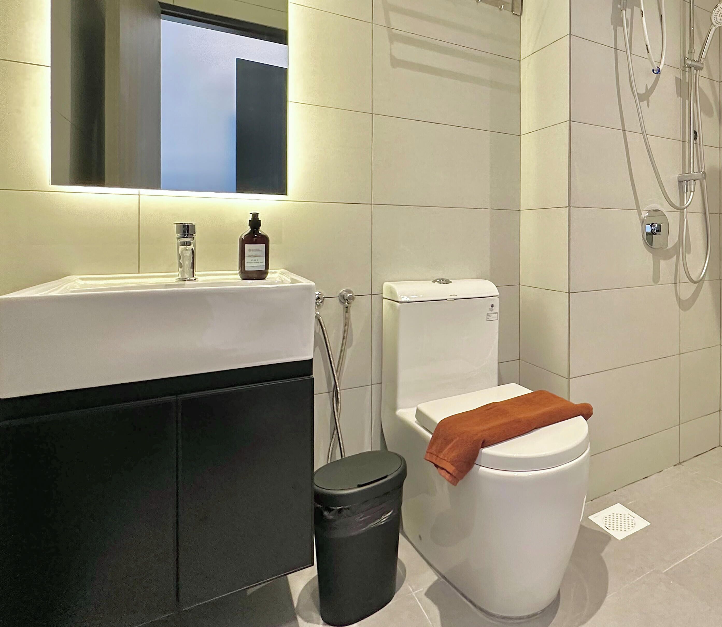 A modern bathroom with a white sink, a toilet, and a shower.