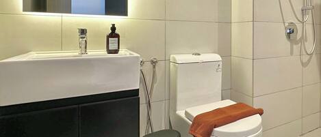 A modern bathroom with a white sink, a toilet, and a shower.