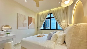 Une chambre à coucher moderne avec un grand lit, une table de chevet, un miroir et une fenêtre avec des rideaux.