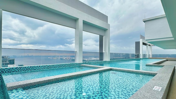 Une piscine à débordement située sur le toit, offrant une vue sur la ville, de grandes fenêtres et une architecture moderne.