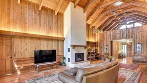 Ein geräumiges Wohnzimmer mit einer großen Ledersofa, einem Kamin, Holzwänden und einem Fernseher.