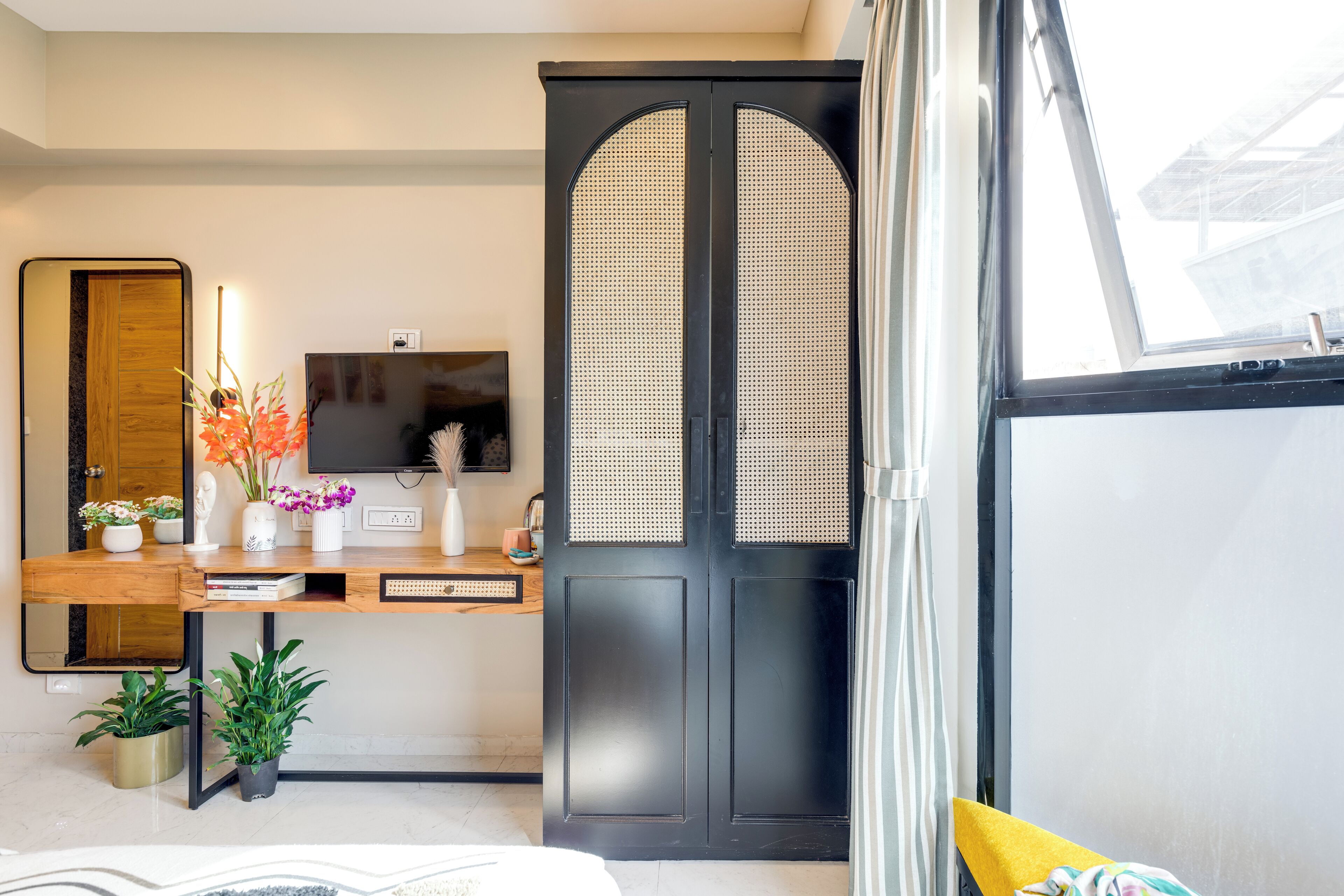 A modern room with a wooden desk, a television, and a large black door with a window.