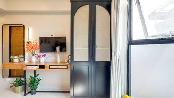 A modern room with a wooden desk, a television, and a large black door with a window.