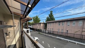 Een balkon met uitzicht op een parkeerplaats en gebouwen.