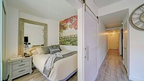 Un dormitorio con cama, mesita de noche y un espejo grande.