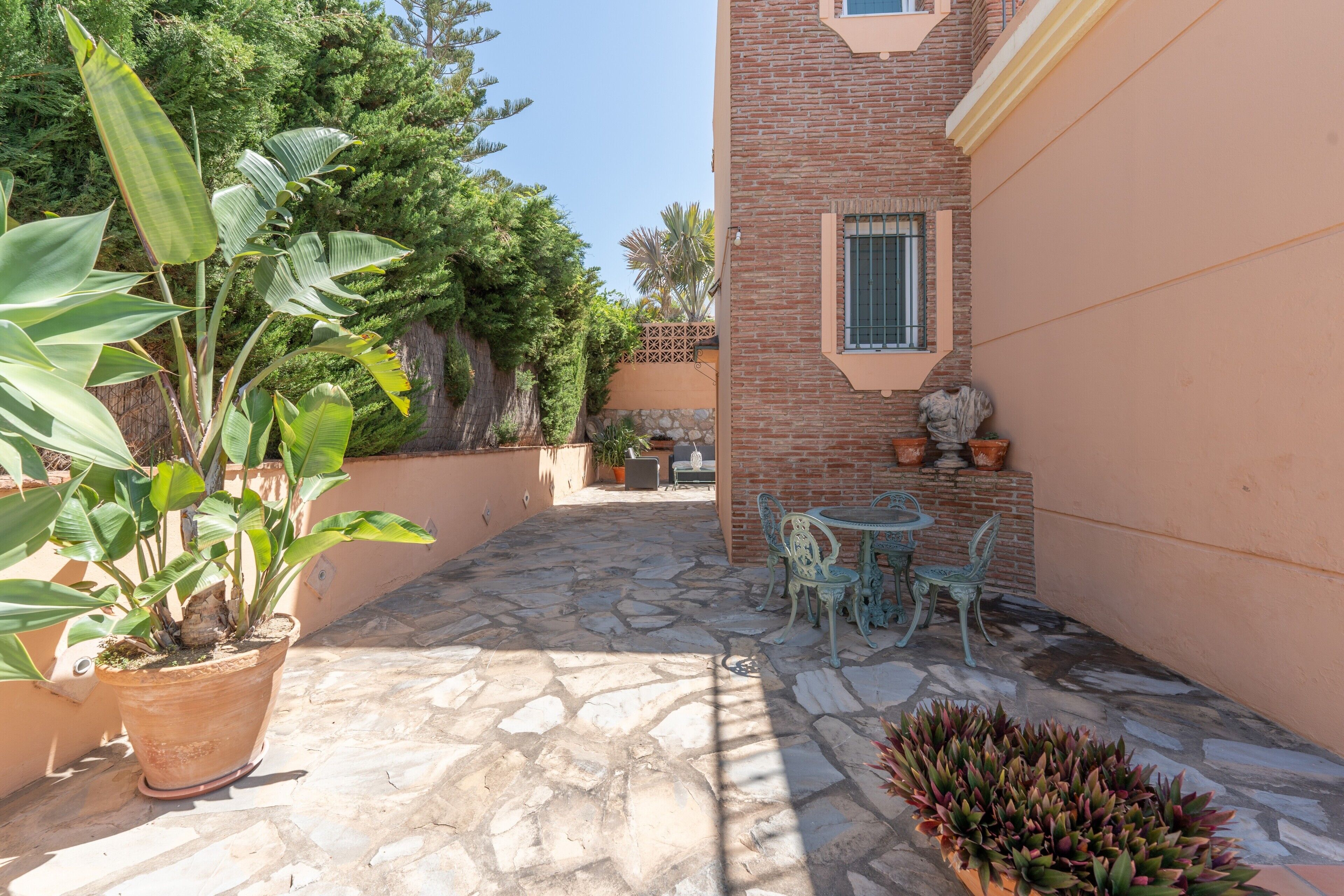 A patio with stone flooring, a potted plant, and a table with chairs.