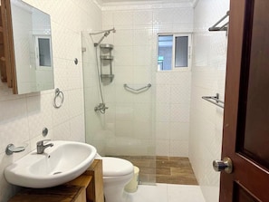 A bathroom with a white sink, toilet, and shower.