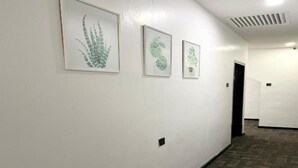 A hallway with three framed botanical prints on the wall, carpeted flooring, and a door at the end. - Gill Garden Boutique Hotel (Malacca City)