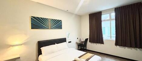 Habitación de hotel con cama, escritorio, silla, ventana con cortinas y una obra de arte colgada en la pared.