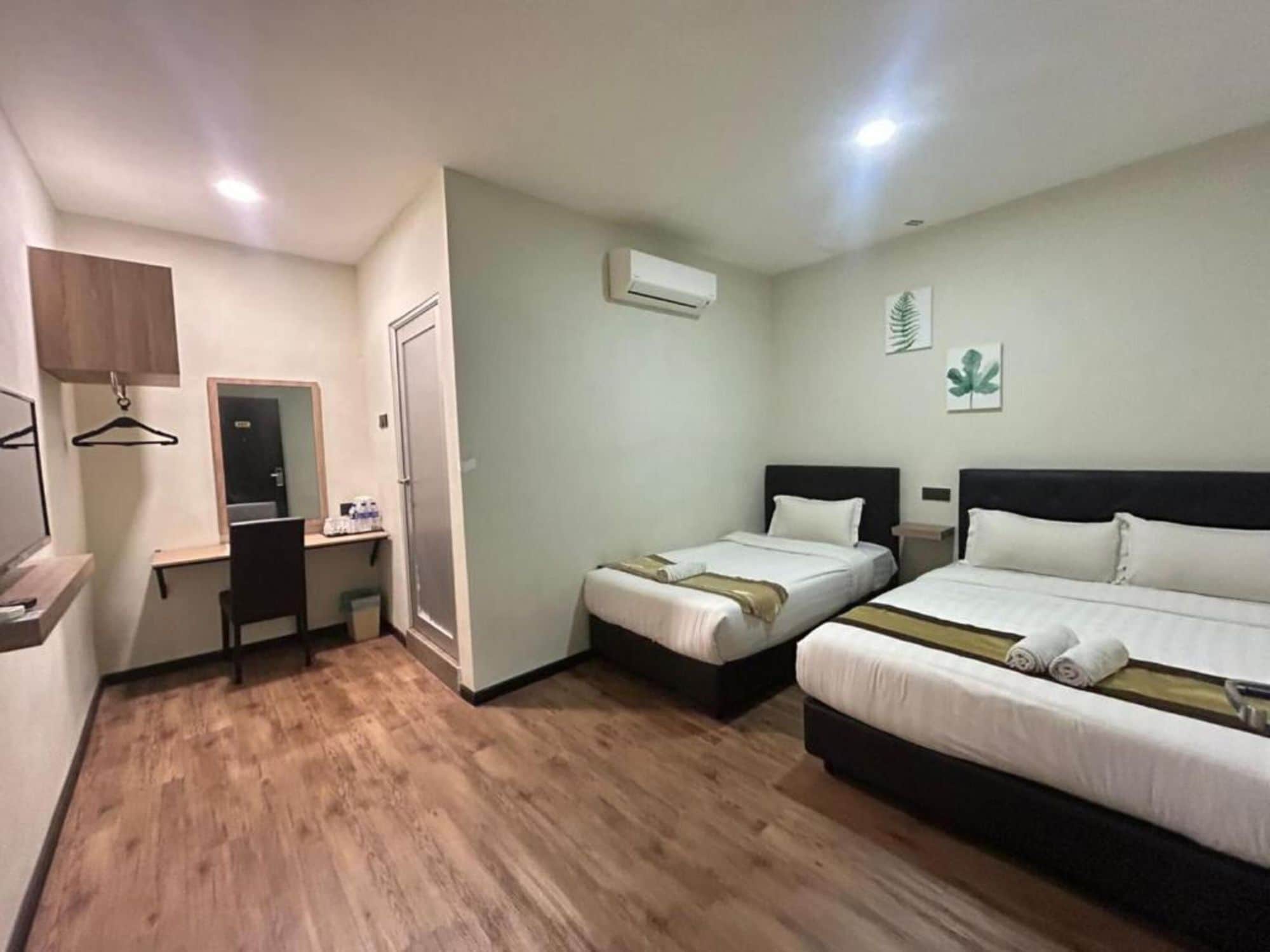 Habitación de hotel con dos camas, un escritorio, una silla, un equipo de aire acondicionado y una puerta.