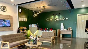 A lobby with a green wall, two sofas, a coffee table, and a reception desk. - Gill Garden Boutique Hotel (Malacca City)