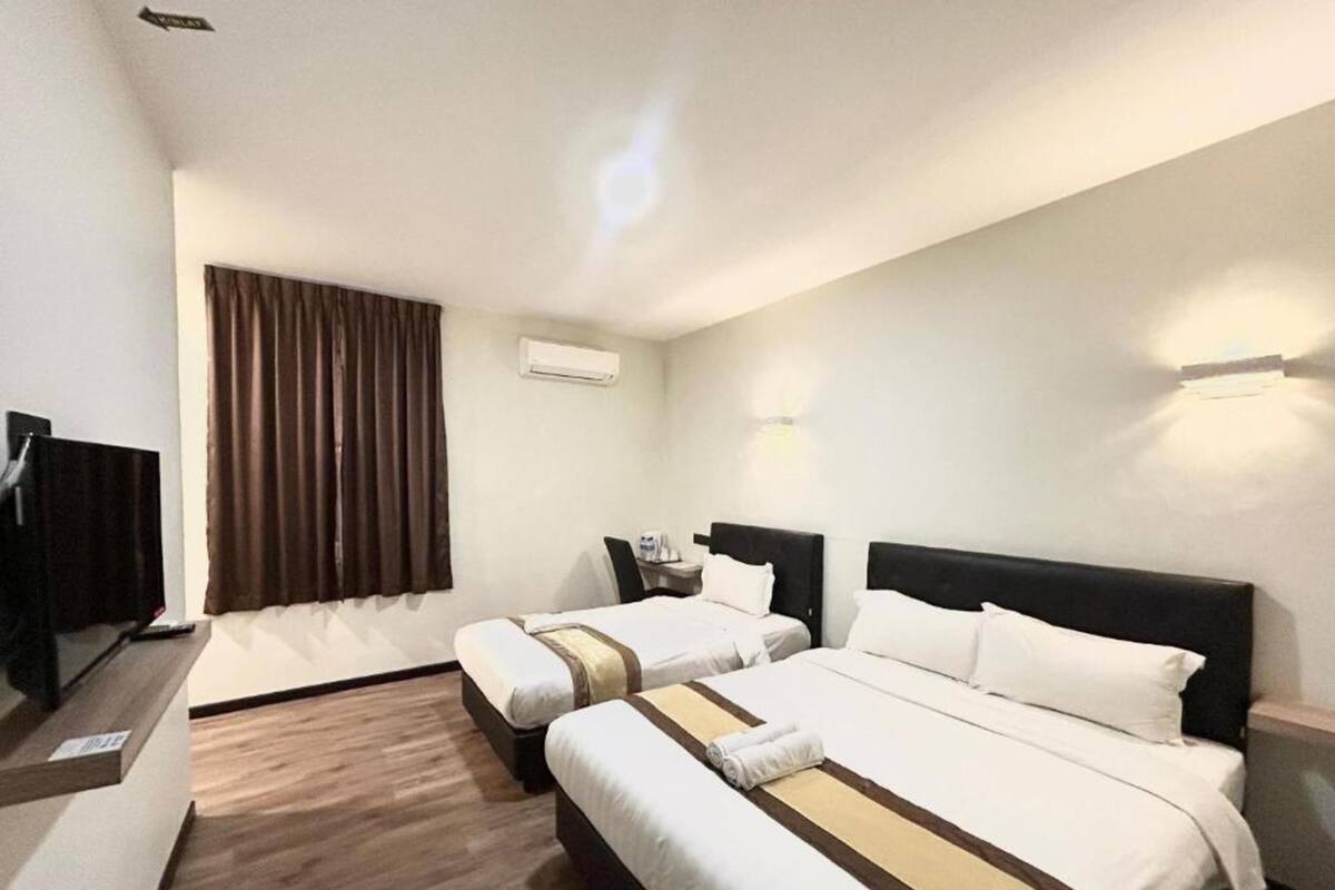 Une chambre d’hôtel avec deux lits, une télévision, un bureau et une fenêtre avec des rideaux.