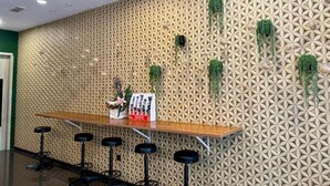 A bar area with a patterned wall, a wooden counter, and black stools. - Gill Garden Boutique Hotel (Malacca City)