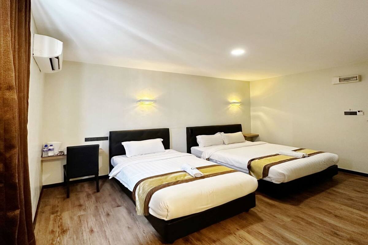 Une chambre d’hôtel avec deux lits simples, une table de chevet, un bureau et une chaise.