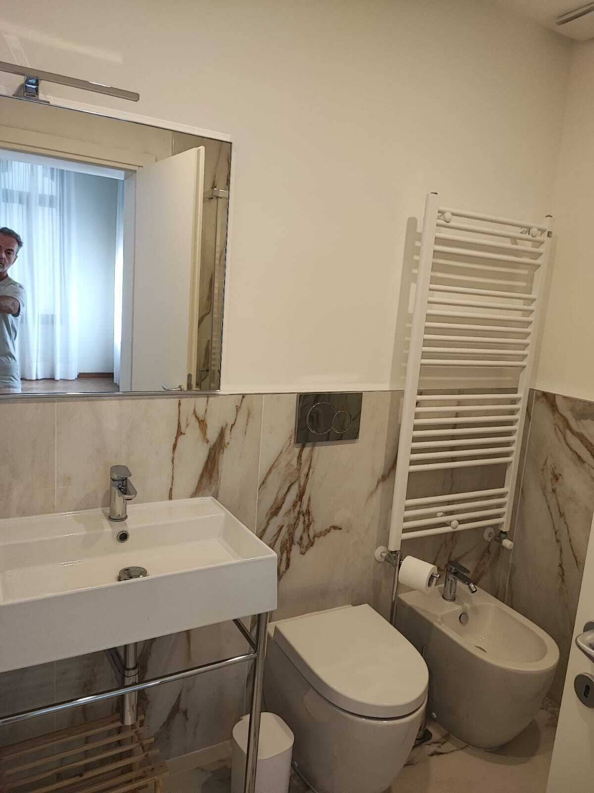Un baño con lavamanos blanco, inodoro, bidé y toallero.