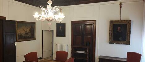 Ein formeller Speisesaal mit einem Holztisch, sechs Stühlen, einer Chandelüster und zwei gerahmten Porträts an den Wänden.