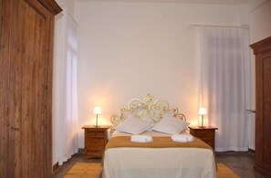 A bedroom with a wooden headboard, two bedside tables with lamps, and a bed with white linens and towels. - Ca degli Stueri (Venice)