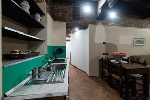 A compact kitchen with a sink, a countertop, and a dining area with a table and chairs. - Ca degli Stueri (Venice)