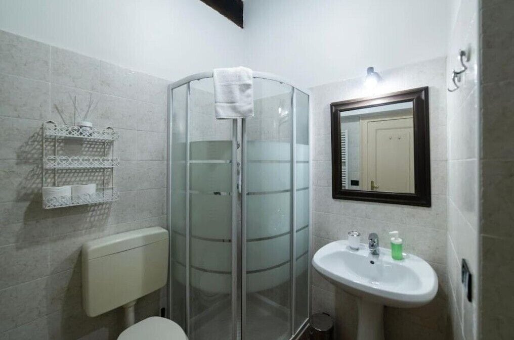 Un baño con cabina de ducha de vidrio, un lavamanos blanco y un espejo.