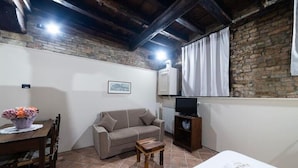 Una habitación acogedora con sofá, una mesa de madera, un televisor sobre un mueble y una pared de ladrillo.