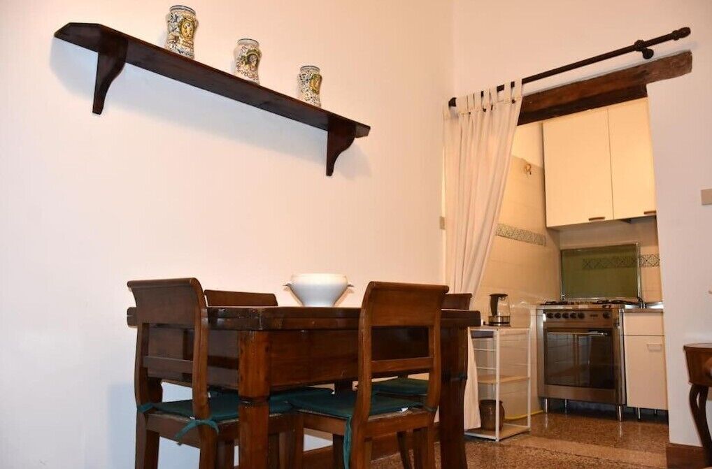 A small kitchen with a stove, oven, and a dining area with a wooden table and chairs.
