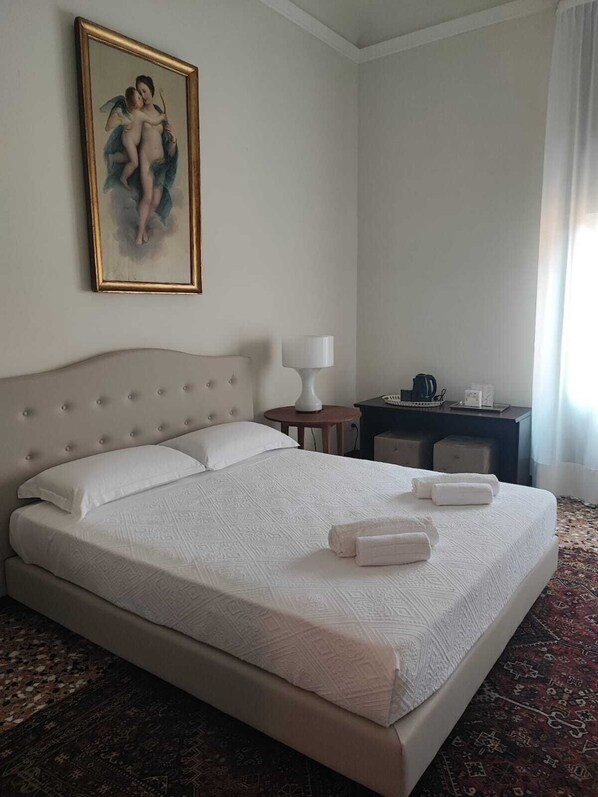 A hotel room with a large bed, a bedside table with a lamp, a desk with a computer, and a painting on the wall. - Ca degli Stueri (Venice)