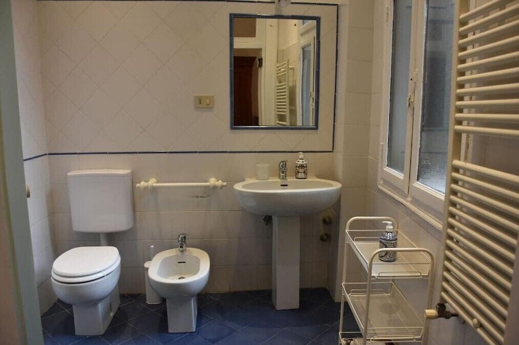 A small bathroom with a toilet, bidet, sink, and a mirror.