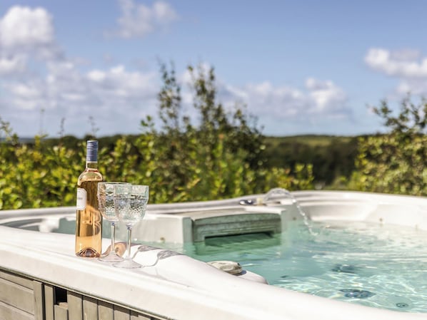 A hot tub with a bottle and glasses on a terrace.