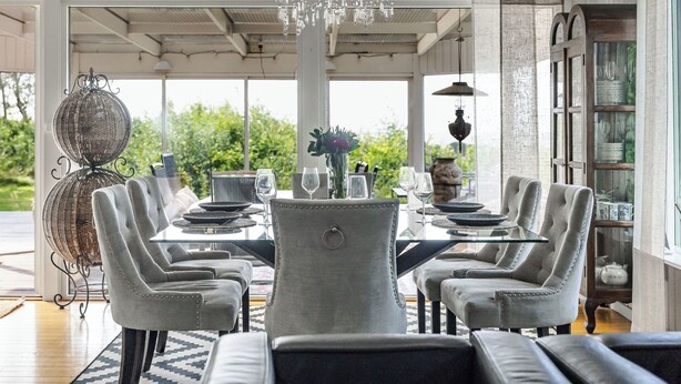 A dining area with a chandelier, a round table, and multiple chairs.