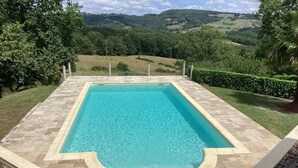 A rectangular swimming pool with a curved edge, surrounded by a stone deck.