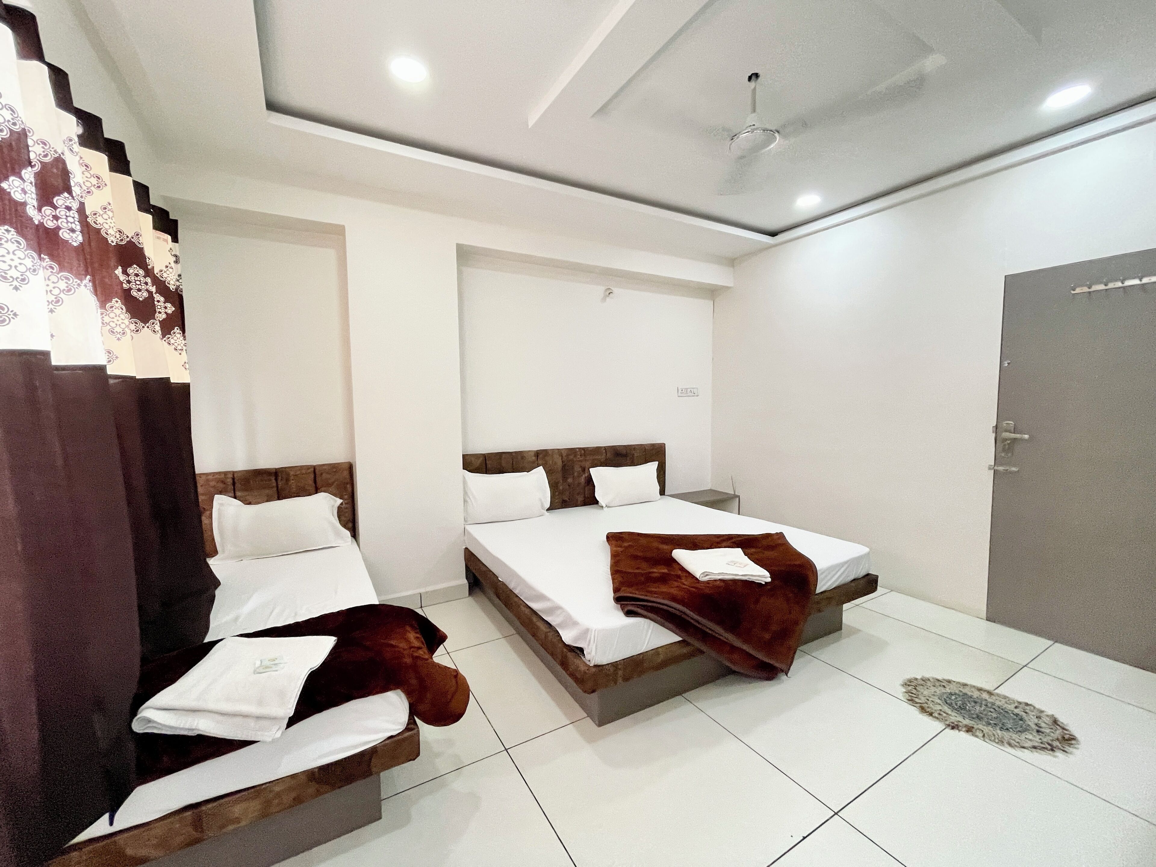 A hotel room with two beds, a ceiling fan, and a door.