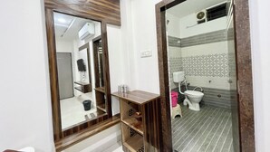 Un baño con tocador de madera, espejo, inodoro y zona de ducha.