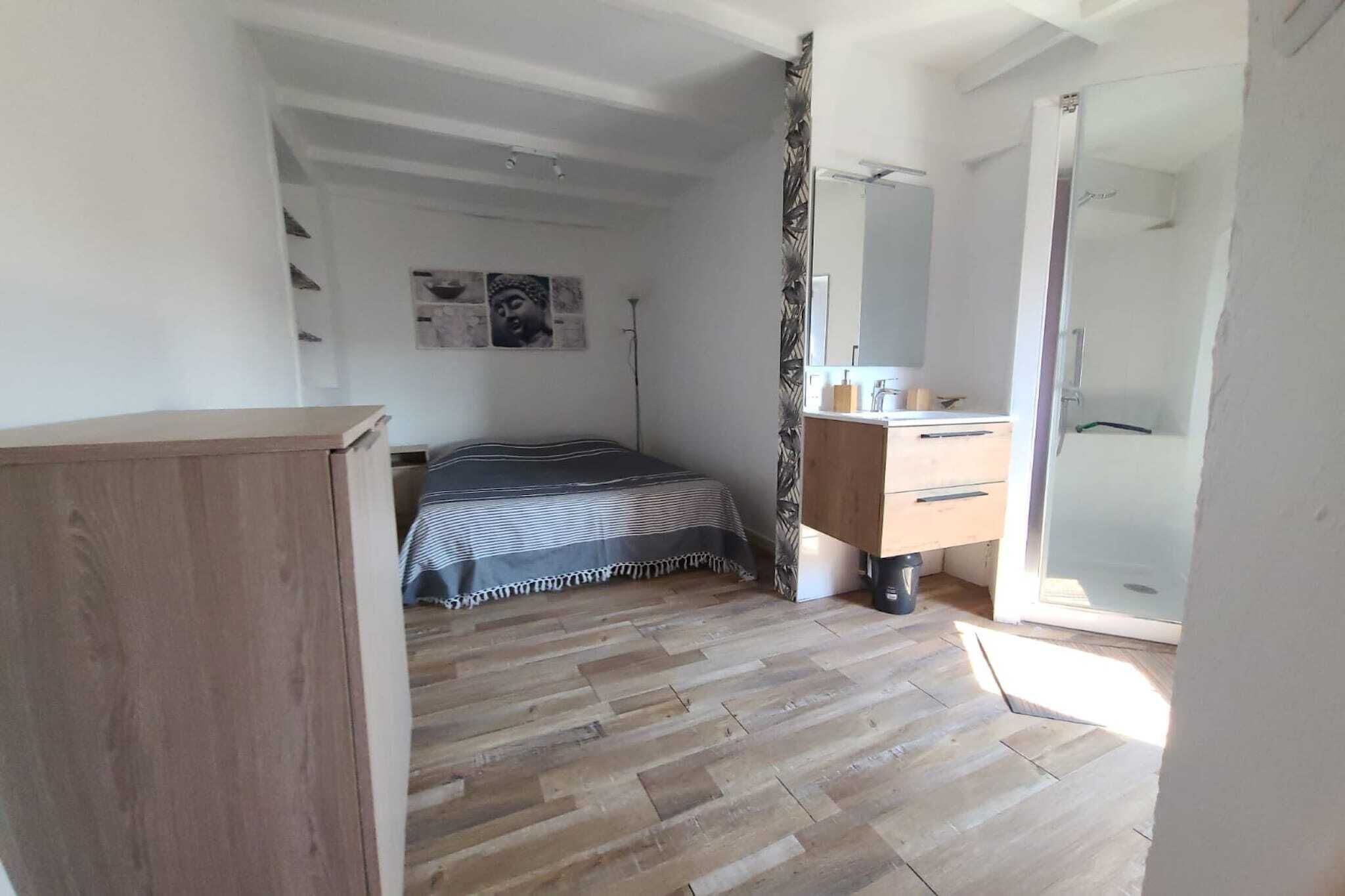 A bedroom with a bed, a wooden dresser, a mirror, and a door leading to a bathroom.