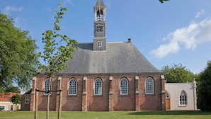 Eine historische Kirche mit einem markanten Glockenturm, Rundbogenfenstern und einer Ziegel-Fassade.