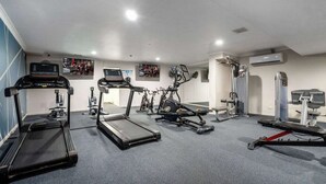 Une salle de sport équipée de tapis de course, de vélos elliptiques et de matériel de musculation.