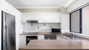 Une cuisine moderne avec des armoires blanches, des appareils en acier inoxydable et un plan de travail en bois.