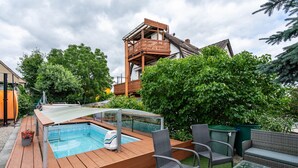 Zwembad met houten terras, omringd door rieten meubels en begroeiing.