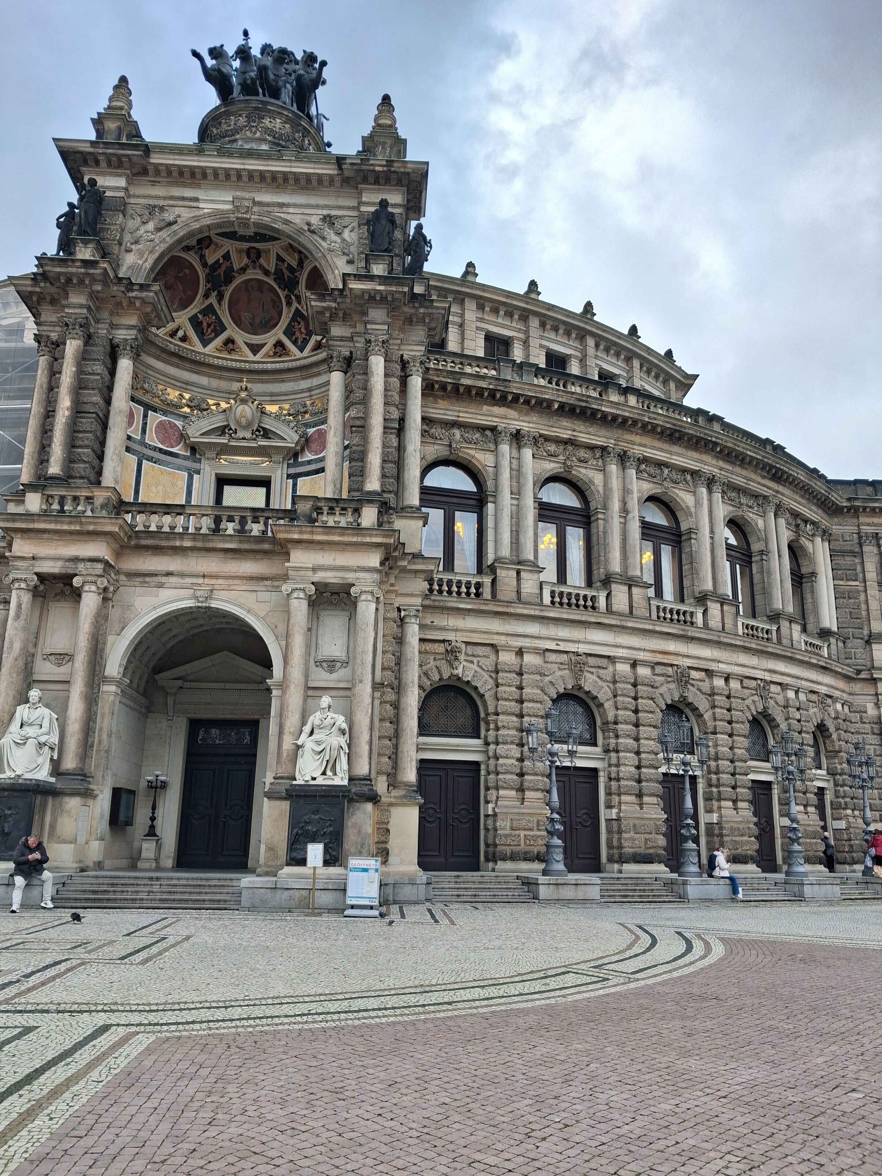 Um edifício histórico com arquitetura ornamentada, grandes janelas em arco e estátuas.